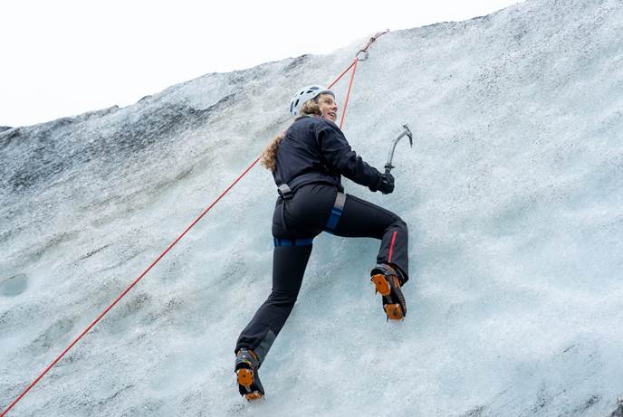 Ice Wall Climb Sólheimajökull  Female using ice axes to climb glacier ice wall at Sólheimajökull