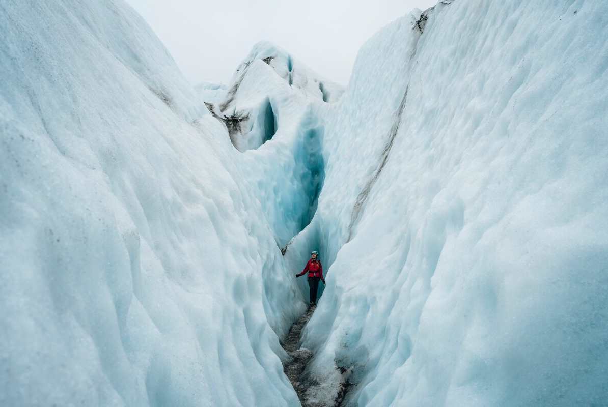 female tourist walking through patterened glacier crevasses.