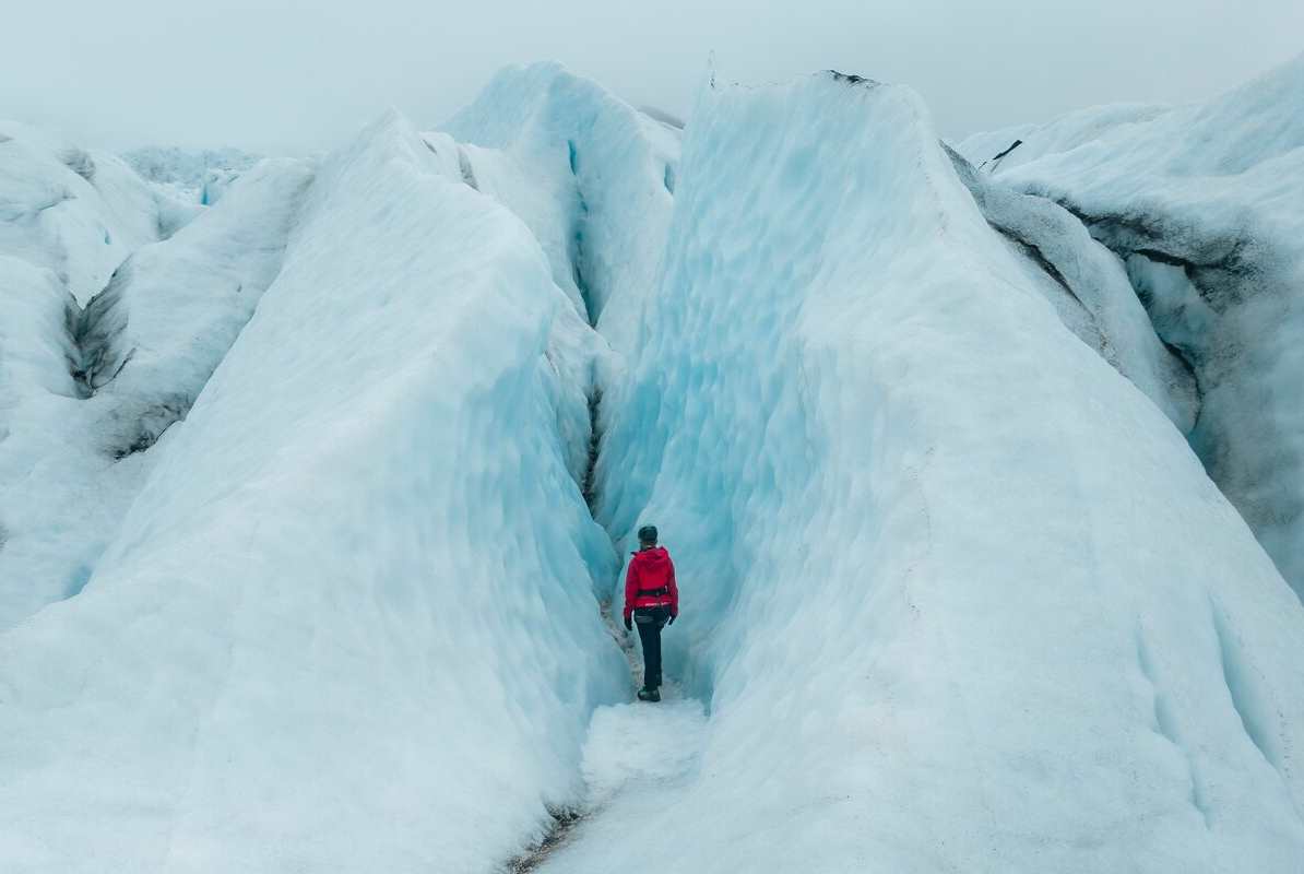 female tourist wandering through blue ice crevasses at Falljokull.