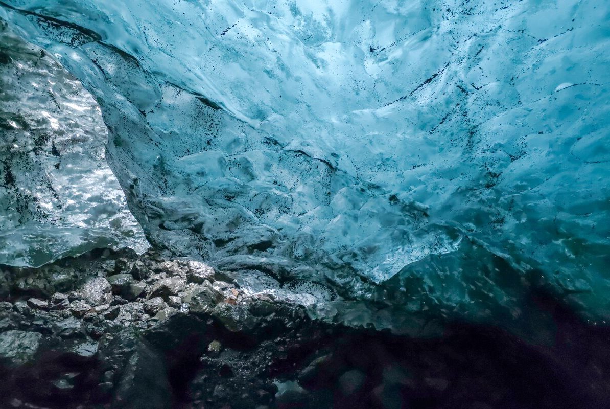 Male standing inside Azure blue ice cave in Solheimajokull.
