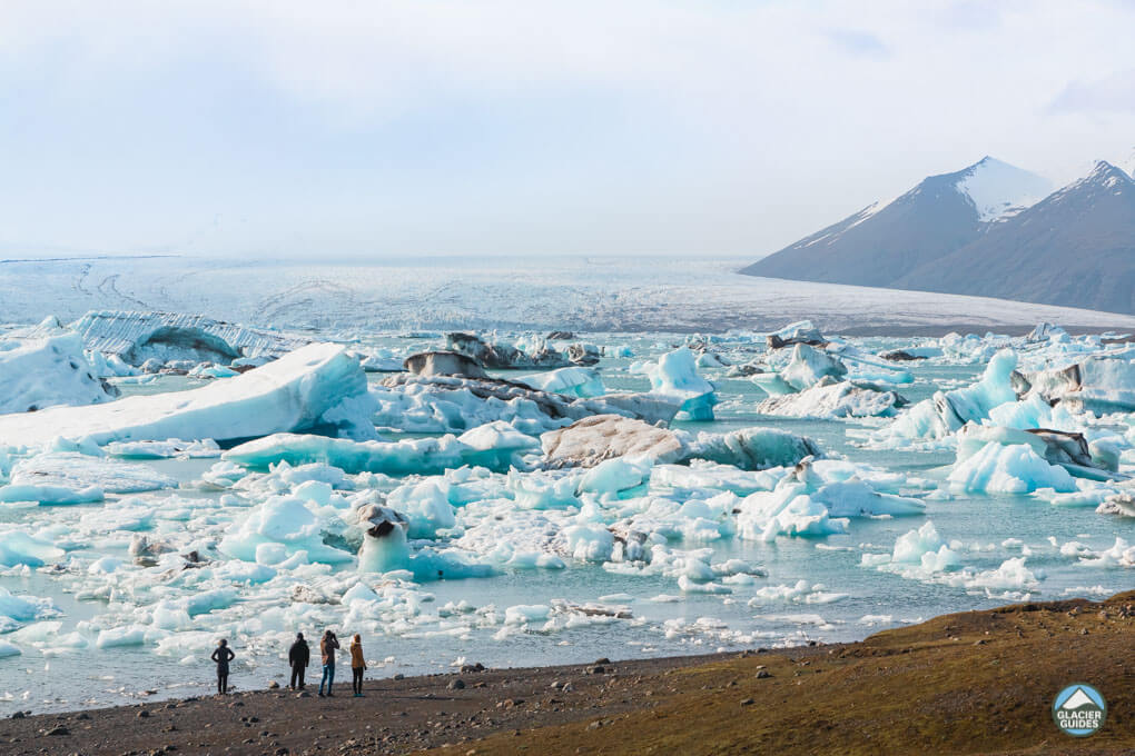 Visitors standing in front of the awe-inspiring icebergs at Jokulsarlon, South Icealnd
