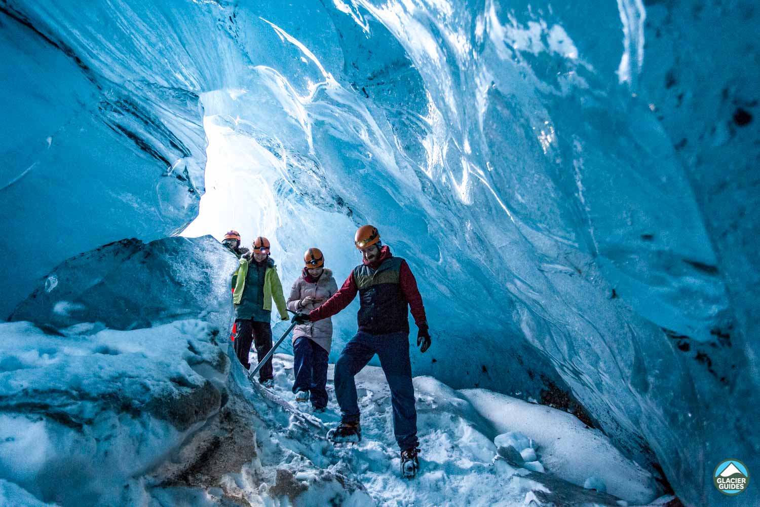 Group Exploring Ice Cave Climbing Down