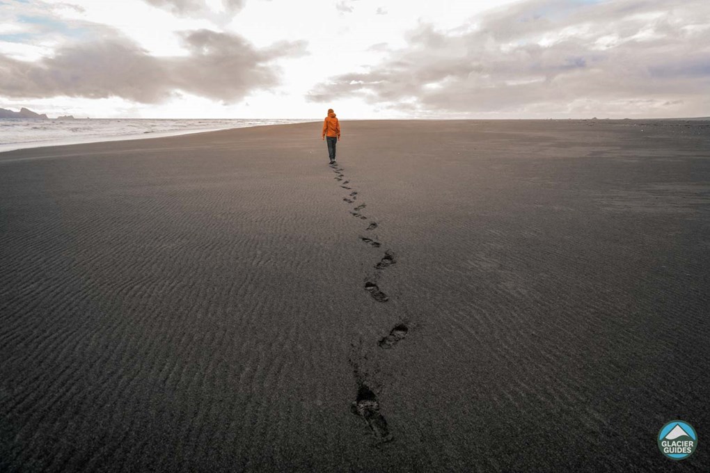 Persons Footprints On Black Sand Beach In Iceland