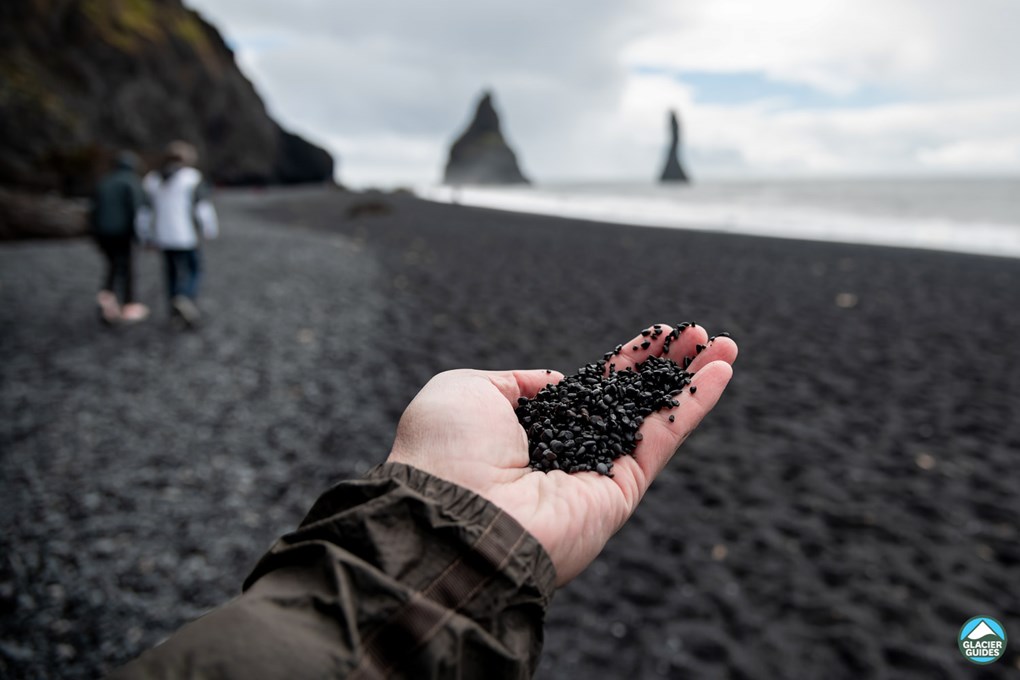 Man hand holding black sand on the Reynisfjara beach