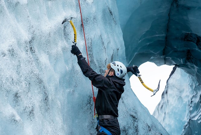 M Ice Climb Man ice climbing on glacier with yellow ice picks