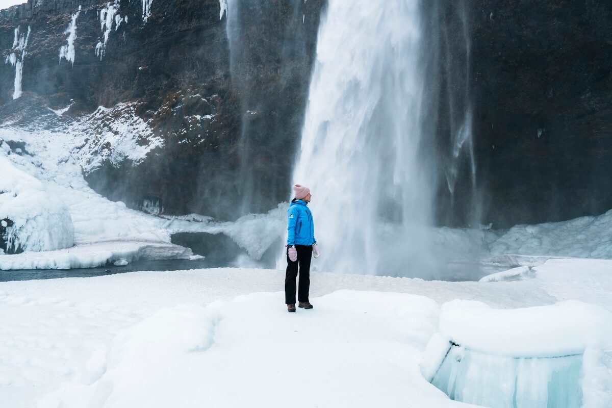 woman in front of seljalandfoss waterfall in winter in iceland