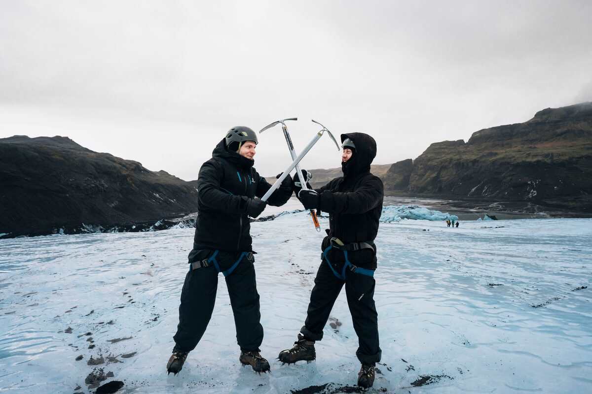 two men crossing picaxes on a glacier in iceland
