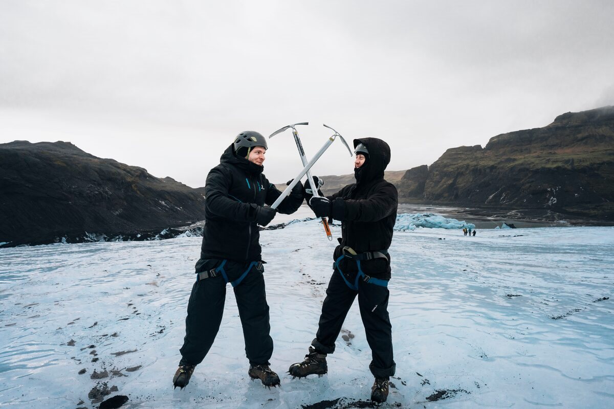 two men crossing picaxes on a glacier in iceland