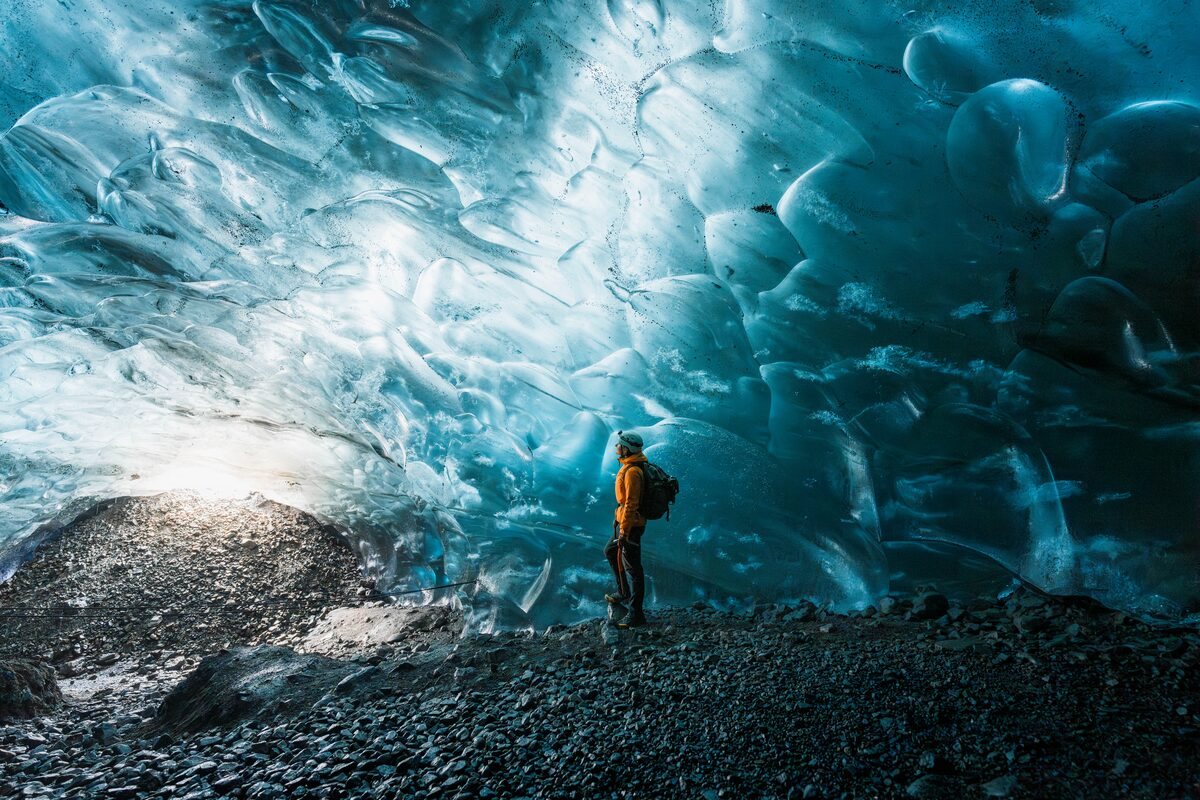 person inside mesmerising crystal ice cave in iceland