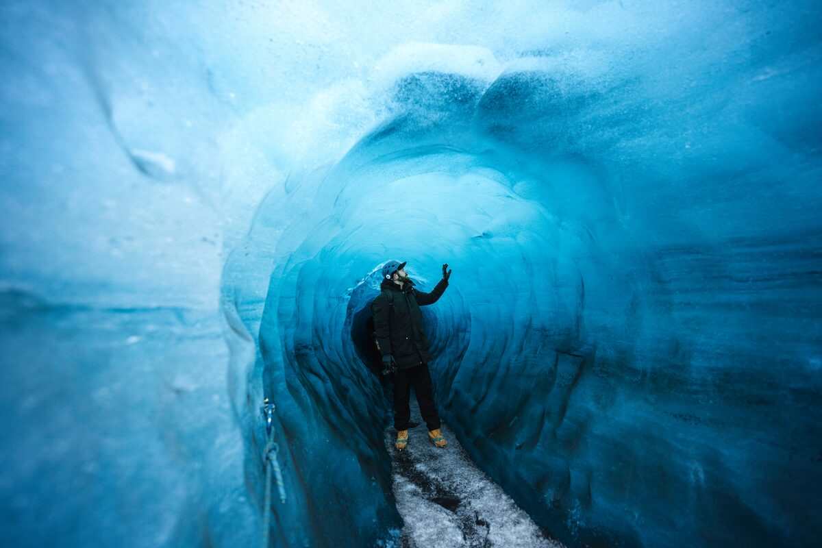 man touching walls inside katla ice cave in iceland