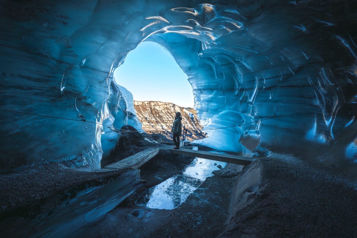 woman standing at the entrance of katla ice cave in iceland