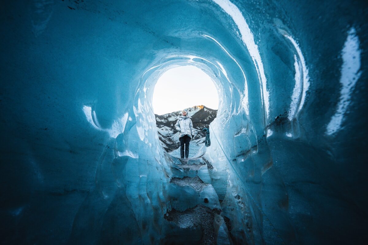 woman standing atop an entrance into katla ice cave in iceland