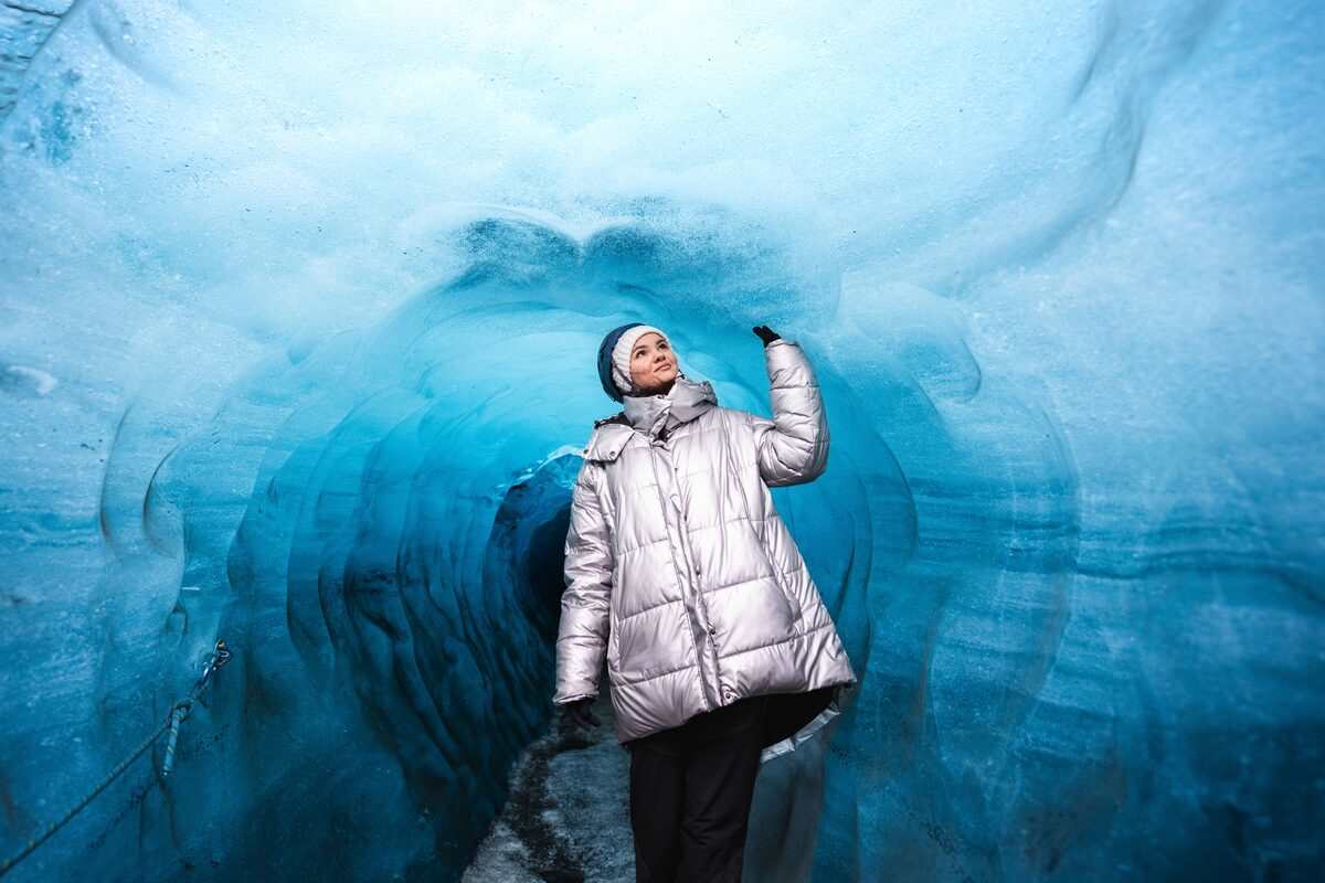 woman touching the walls of katla ice cave in iceland
