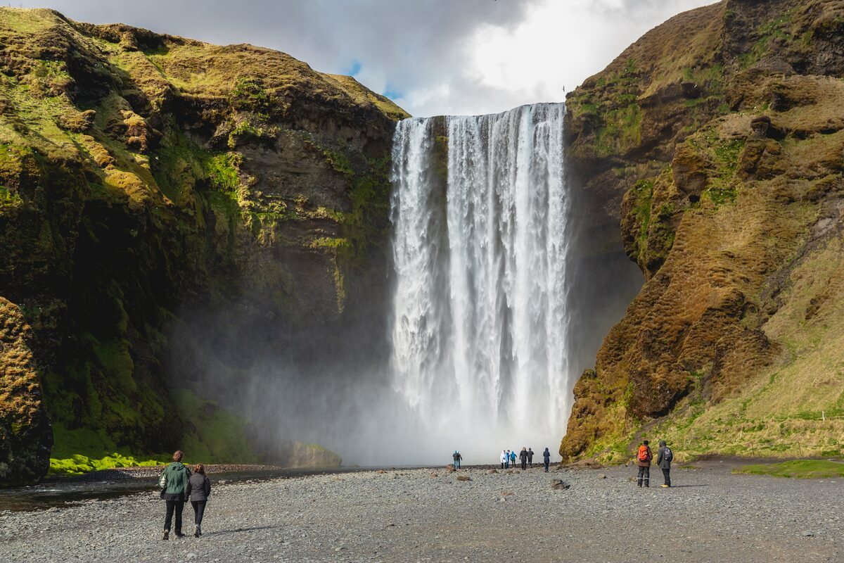 People Walking At Skogafoss Waterfall in iceland
