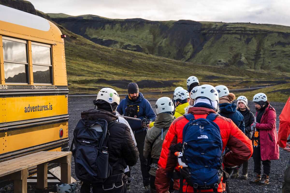 people listening to guide before glacier hike near a bus in iceland