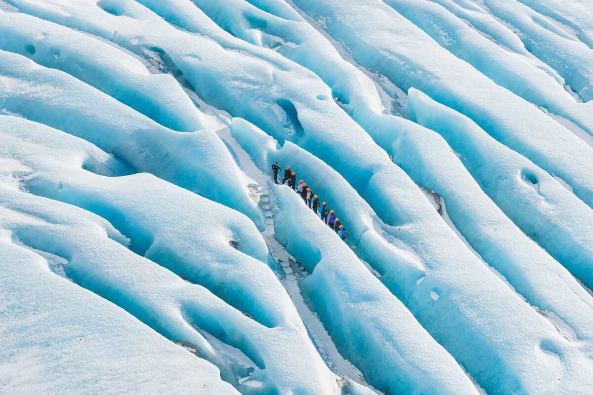 Group Of People Walking Through Glacier Crevasses in Iceland