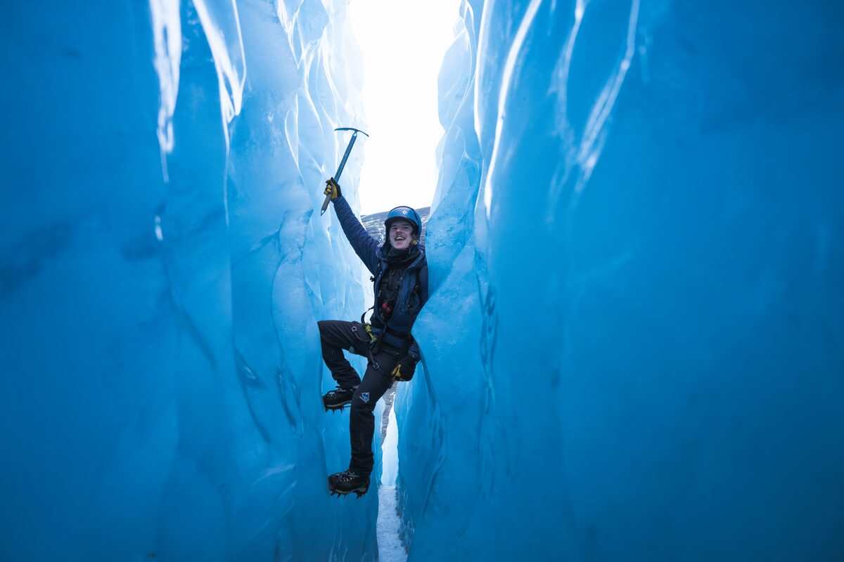 Person With A Pickaxe Between Two Glacier Crevasse Walls in Iceland